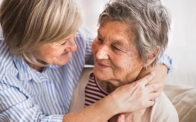 Woman hugging elderly woman indoors