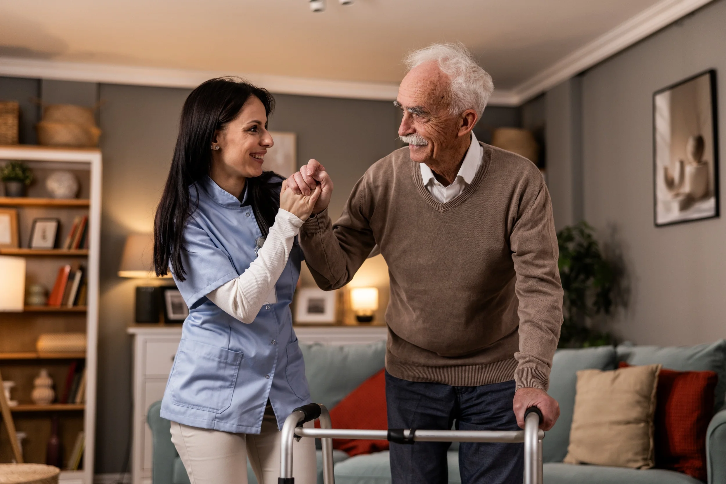 Caregiver assisting elderly man with walker at home