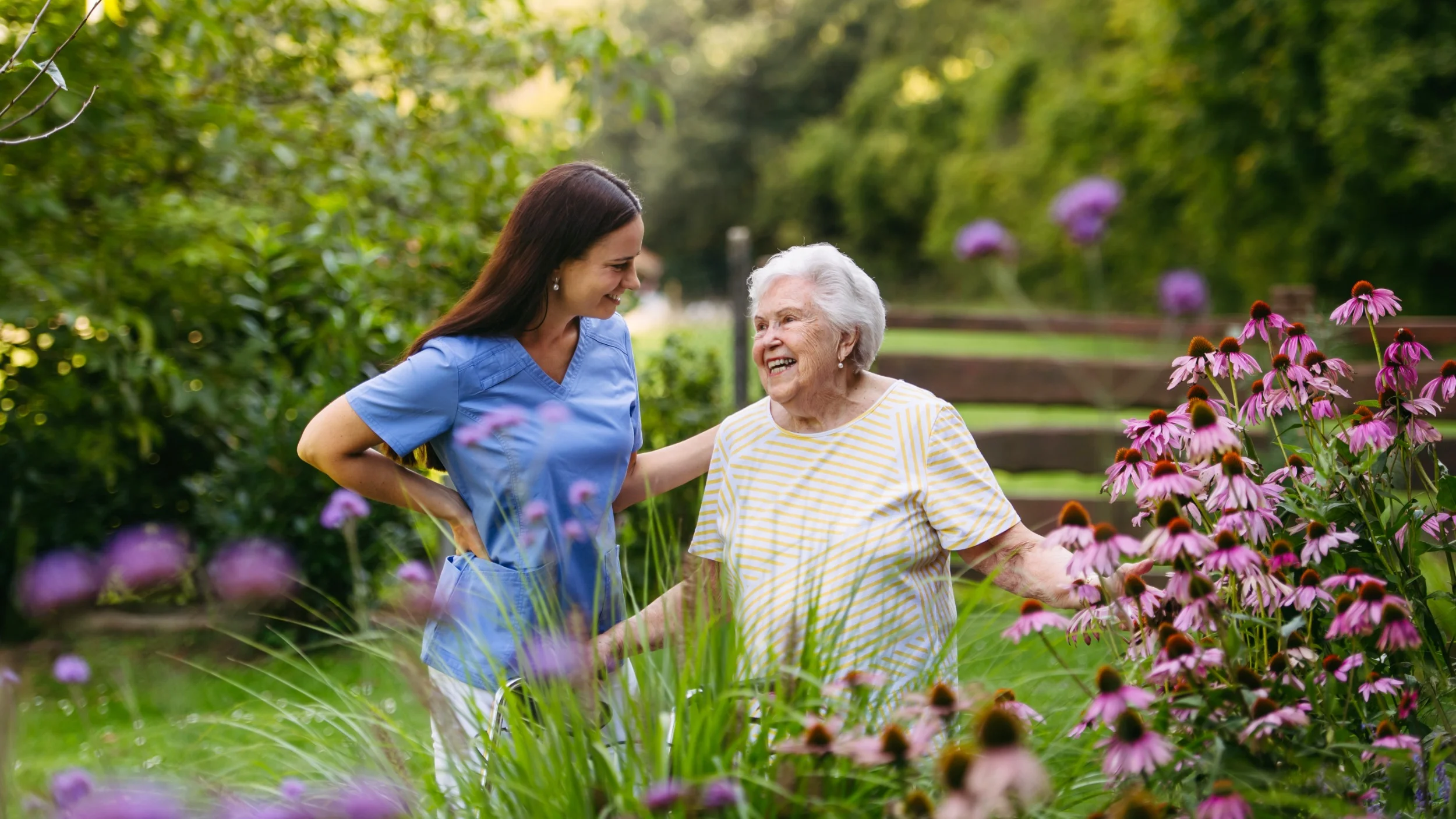 Caregiver and elderly woman smiling in garden