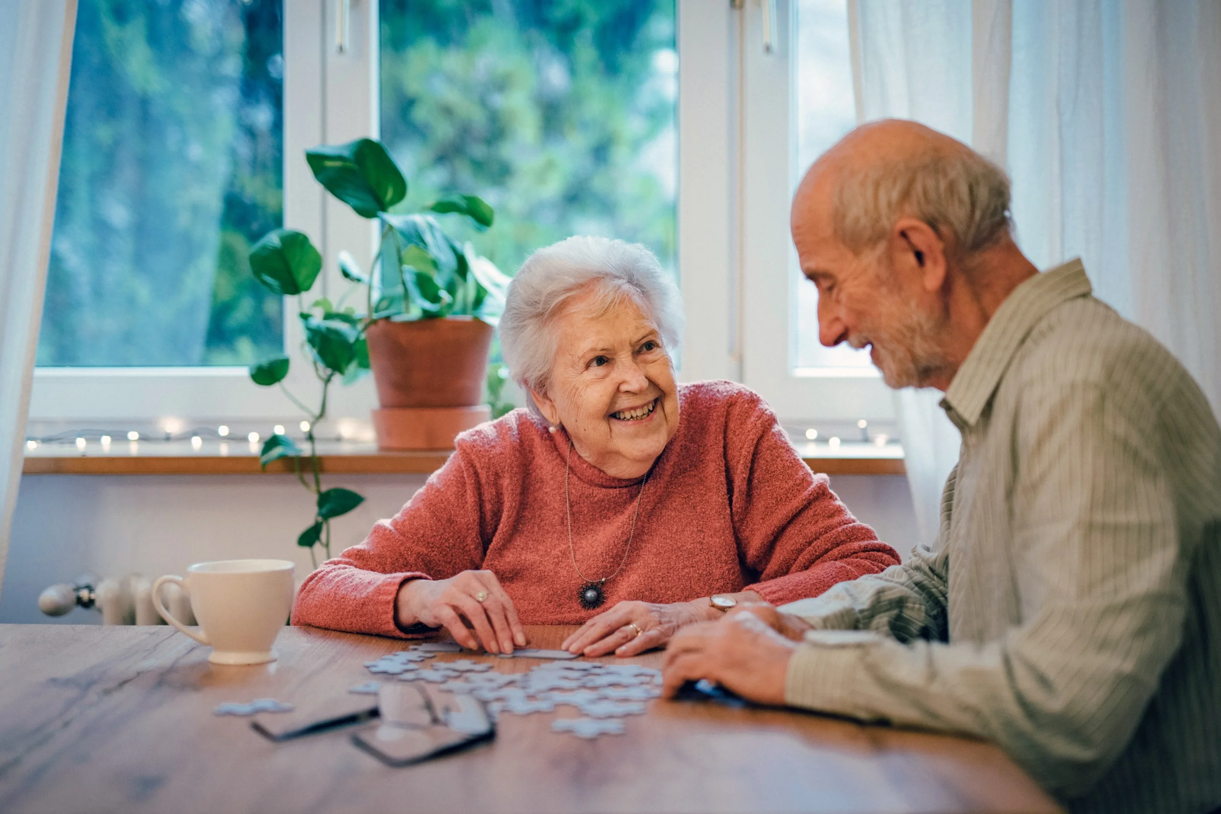 Elderly couple smiling while doing puzzle together