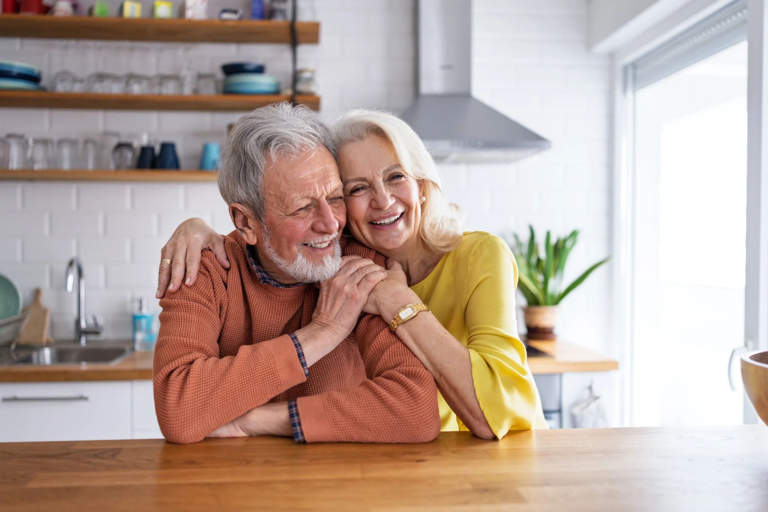Smiling senior couple embracing at kitchen table