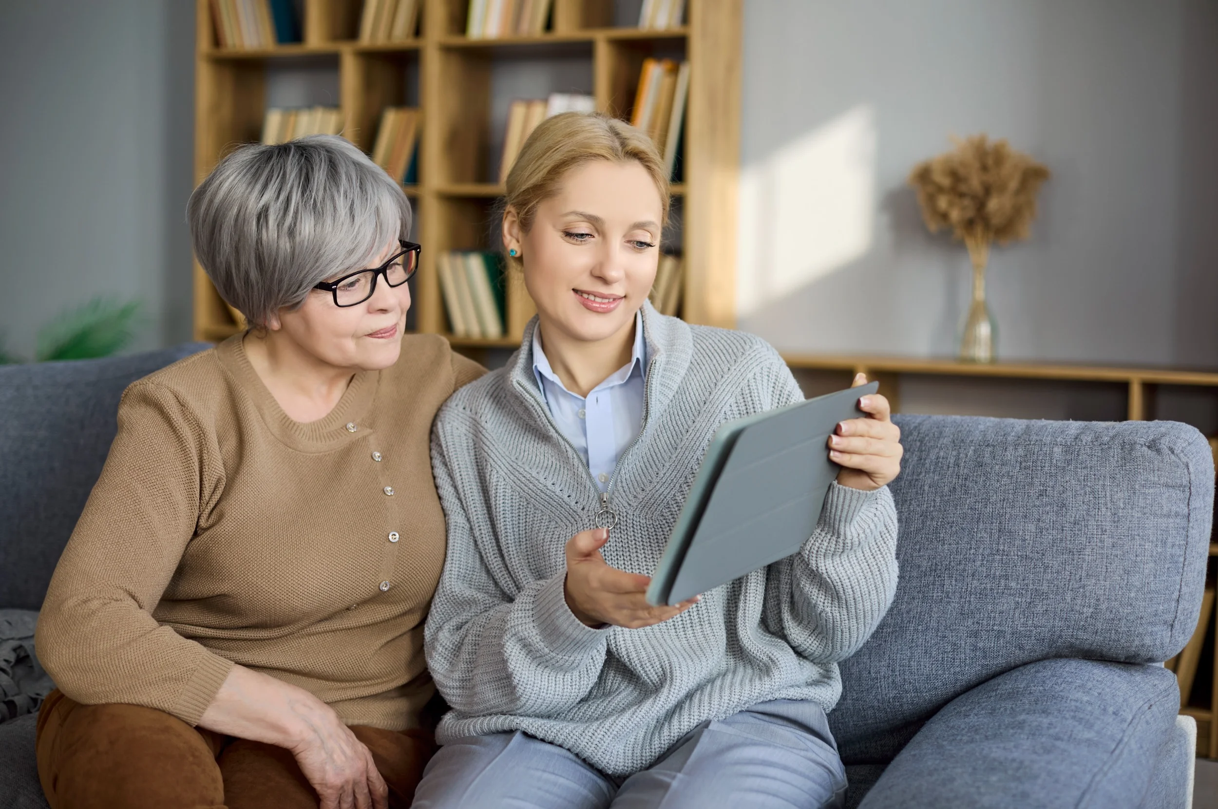 Two women looking at tablet on couch