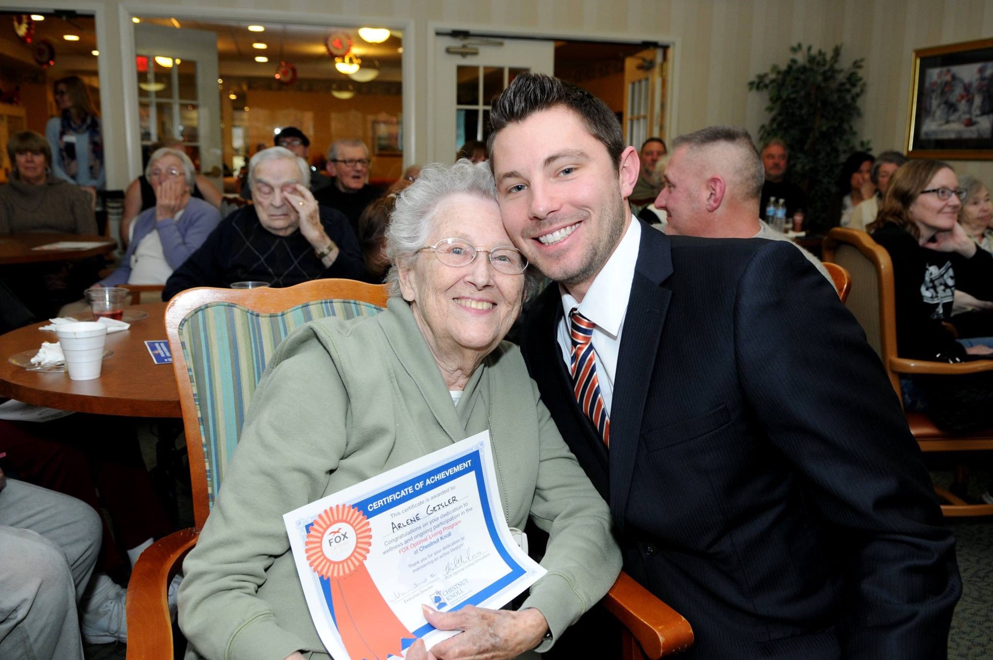 Elderly woman holding certificate with smiling man