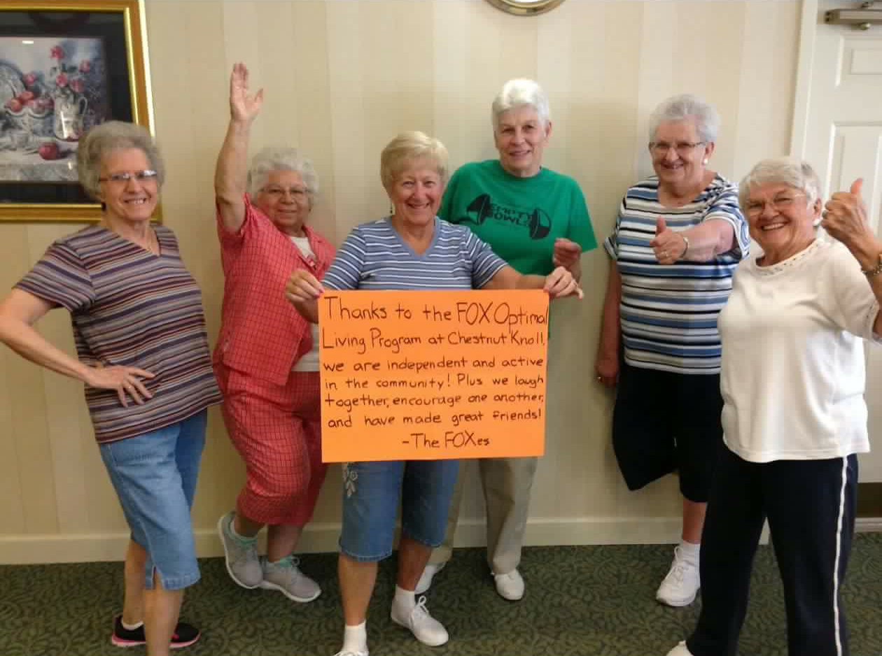 Senior women holding thank-you sign indoors