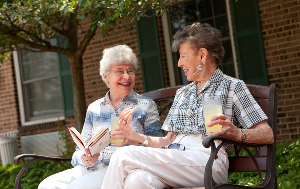 Two elderly women chatting on outdoor bench