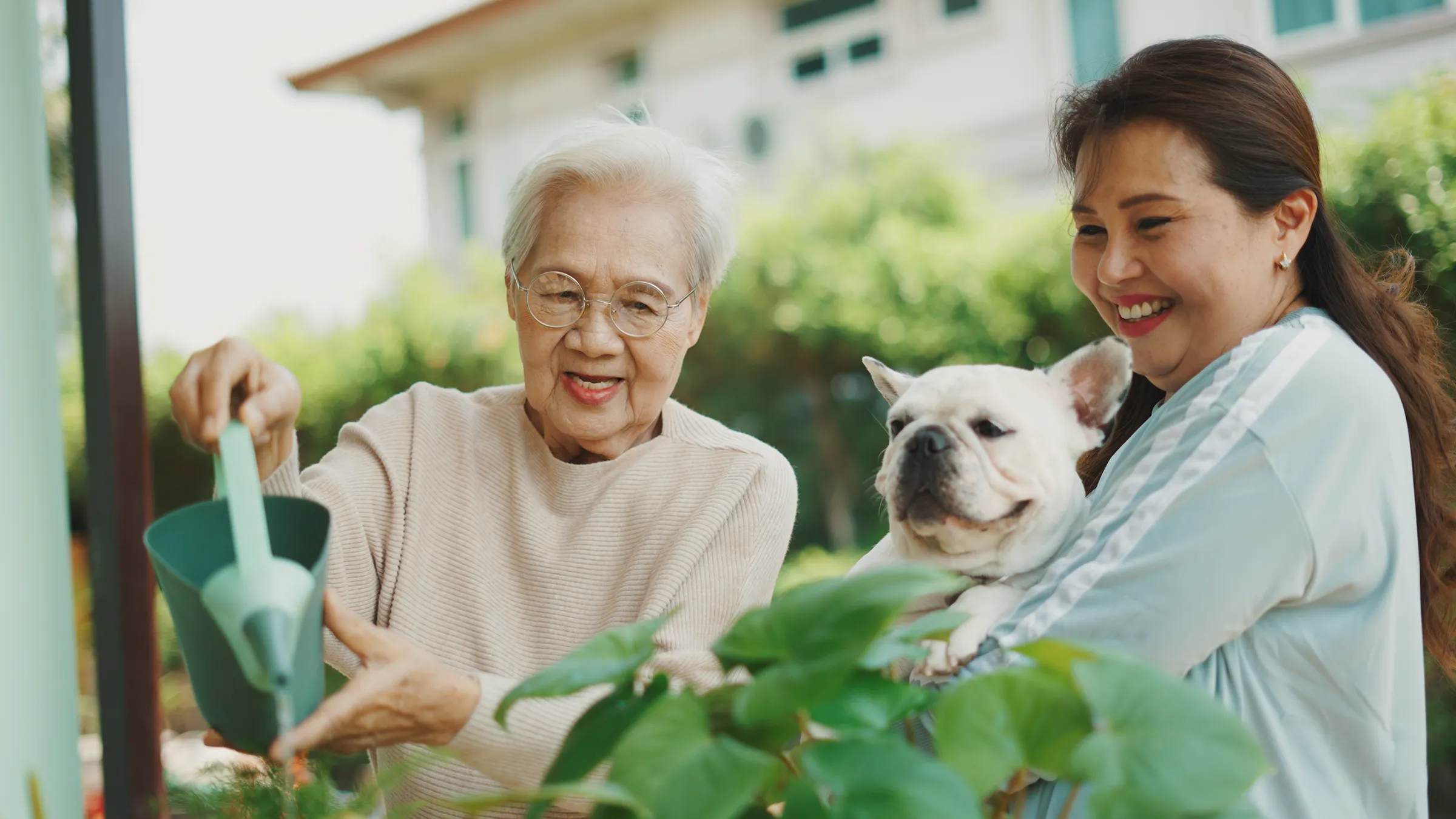 Elderly woman watering plants with family and dog